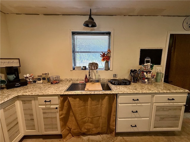 kitchen featuring white cabinets, sink, hanging light fixtures, hardwood / wood-style flooring, and light stone countertops