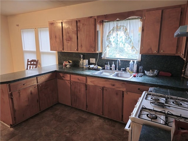 kitchen with backsplash, kitchen peninsula, white gas range oven, and sink