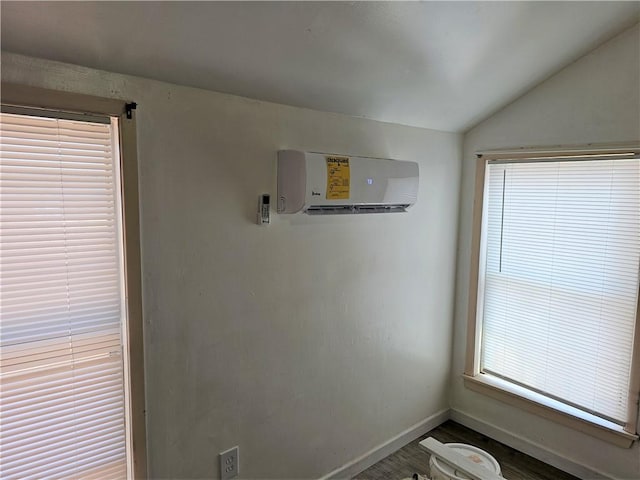 interior space featuring lofted ceiling, a wall mounted AC, and hardwood / wood-style floors