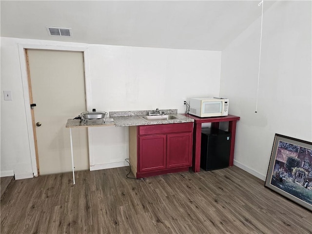 kitchen featuring vaulted ceiling, dark wood-type flooring, sink, and refrigerator