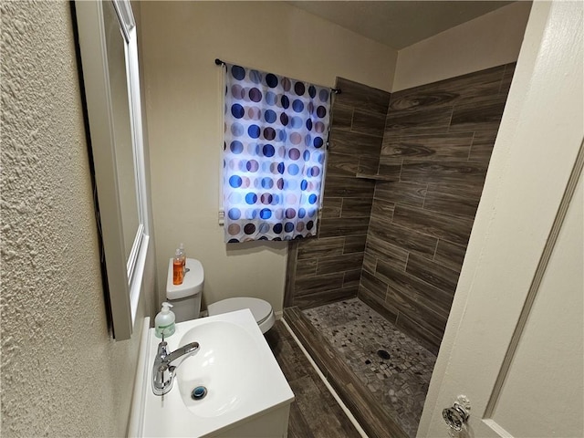 bathroom featuring sink, toilet, and tiled shower