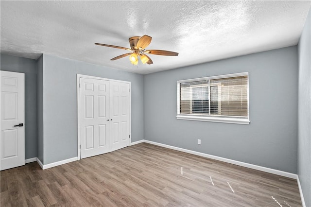 10946 Birdwood, Corpus Christi, TX 78410 - unfurnished bedroom with wood finished floors, a closet, baseboards, a textured ceiling, and ceiling fan