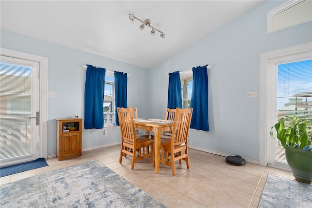 dining area with plenty of natural light, rail lighting, light tile patterned floors, and vaulted ceiling