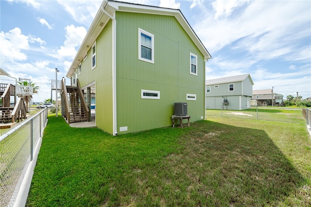 rear view of property with a lawn, a wooden deck, and cooling unit