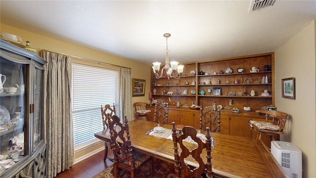 dining area featuring visible vents, a healthy amount of sunlight, an inviting chandelier, and dark wood-style floors