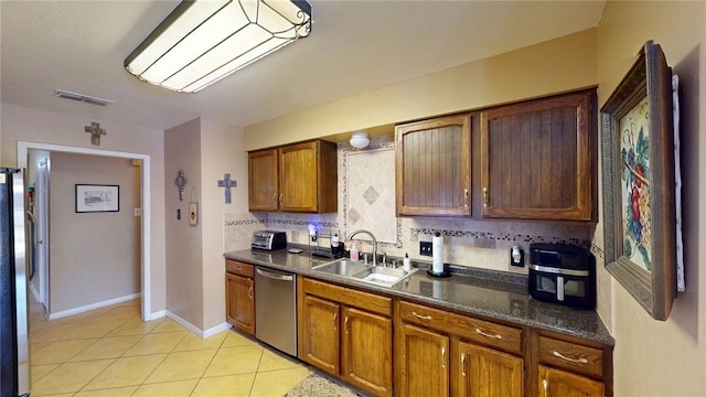kitchen with appliances with stainless steel finishes, dark countertops, visible vents, decorative backsplash, and a sink