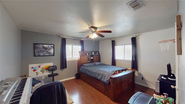 bedroom featuring visible vents, baseboards, wood finished floors, and a textured ceiling