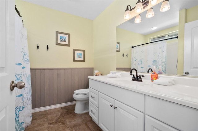 bathroom with vanity, wood walls, and toilet