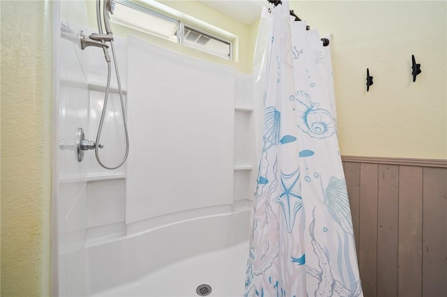 bathroom with a shower with shower curtain and wooden walls