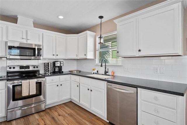 kitchen with white cabinets, decorative backsplash, sink, and stainless steel appliances