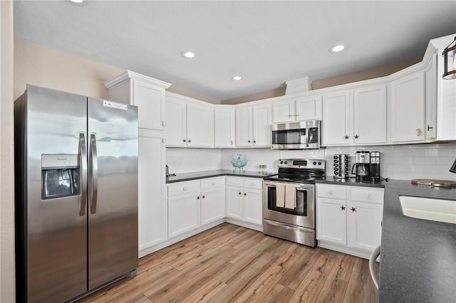 kitchen with white cabinets, sink, light wood-type flooring, appliances with stainless steel finishes, and tasteful backsplash