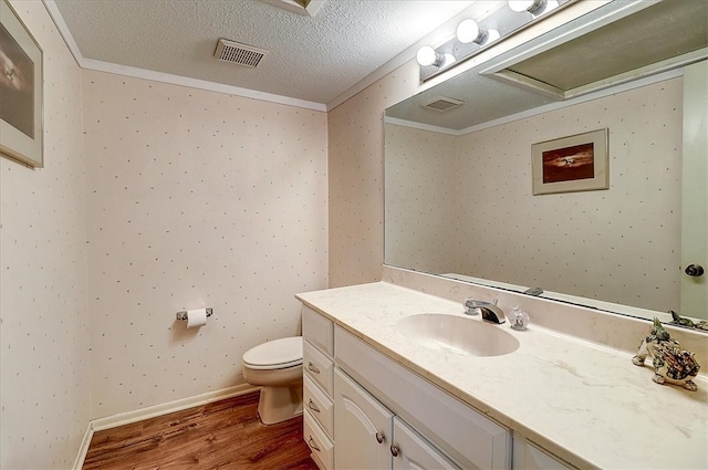 bathroom with ornamental molding, vanity, a textured ceiling, hardwood / wood-style flooring, and toilet