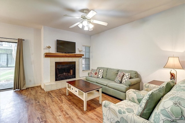 living room featuring a fireplace, light hardwood / wood-style floors, and ceiling fan