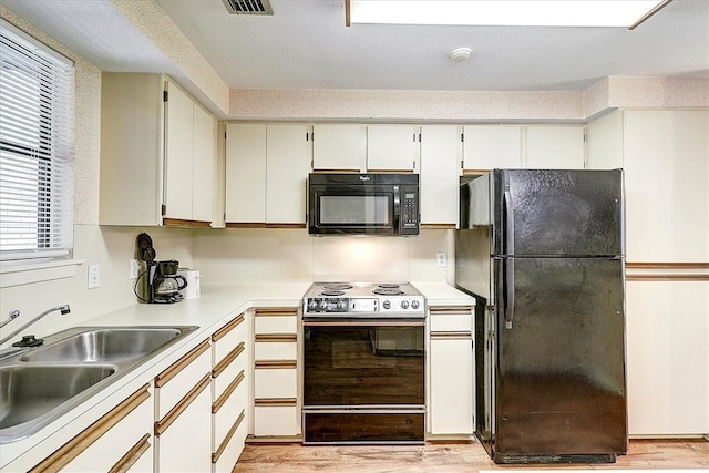 kitchen featuring white cabinets, light wood-type flooring, black appliances, and sink