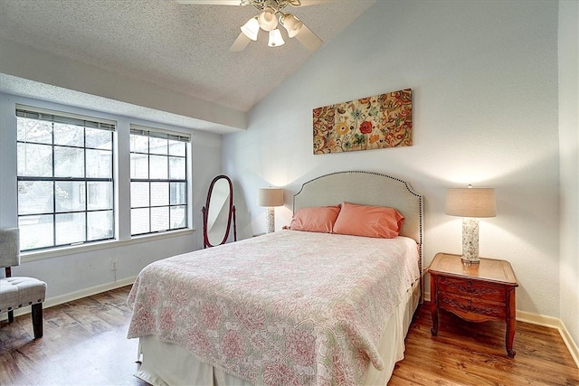 bedroom with lofted ceiling, wood-type flooring, ceiling fan, and a textured ceiling