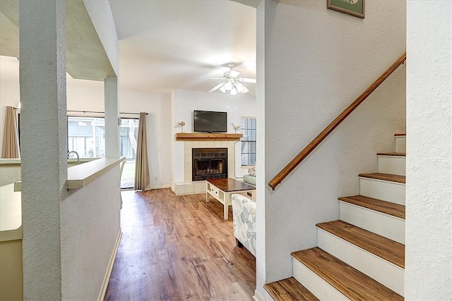 living room featuring light hardwood / wood-style floors, ceiling fan, and a tile fireplace