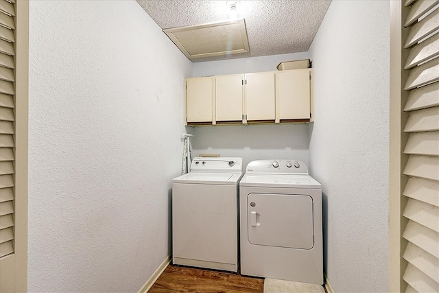 washroom with a textured ceiling, dark wood-type flooring, cabinets, and washer and dryer