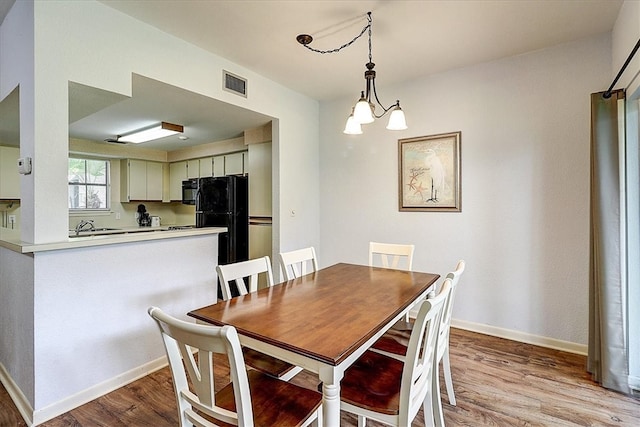 dining area with light hardwood / wood-style floors and a notable chandelier