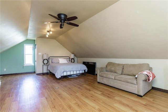 bedroom with lofted ceiling, baseboards, and light wood-style floors