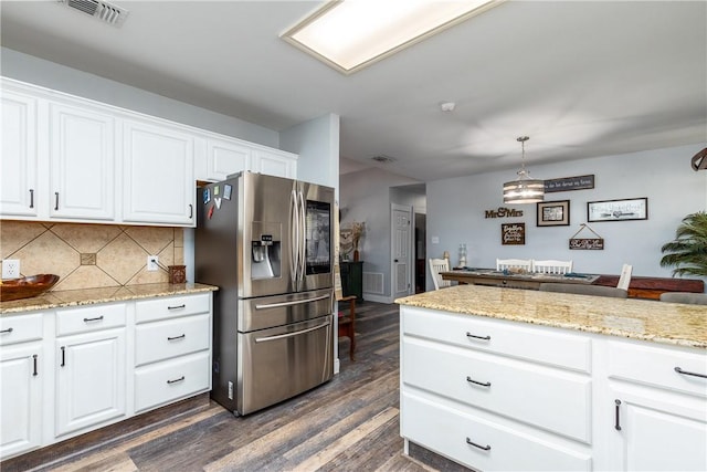 kitchen with dark wood-type flooring, visible vents, white cabinets, stainless steel fridge with ice dispenser, and decorative backsplash