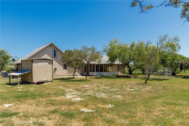 back of house featuring an outbuilding, a sunroom, a lawn, and a storage shed