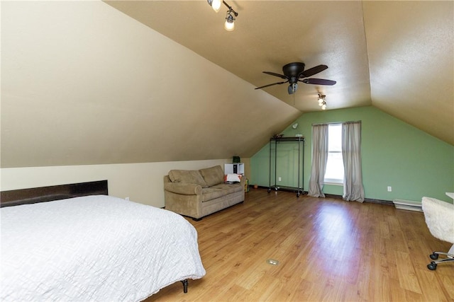 bedroom featuring a ceiling fan, a baseboard radiator, vaulted ceiling, and wood finished floors