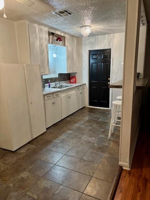 1125 Woodlawn Dr, Corpus Christi, TX 78412 - kitchen featuring visible vents, white cabinetry, light countertops, a textured ceiling, and a sink