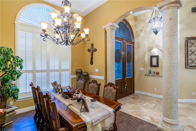 dining space with hardwood / wood-style floors, a chandelier, french doors, and decorative columns