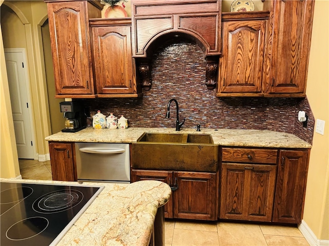 kitchen with sink, light stone counters, light tile patterned floors, stainless steel dishwasher, and decorative backsplash