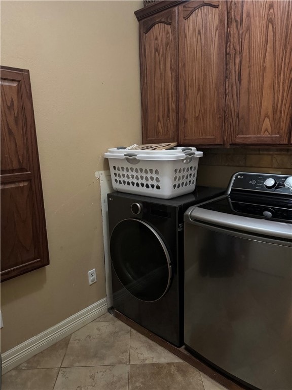 washroom featuring cabinets, independent washer and dryer, and light tile patterned floors