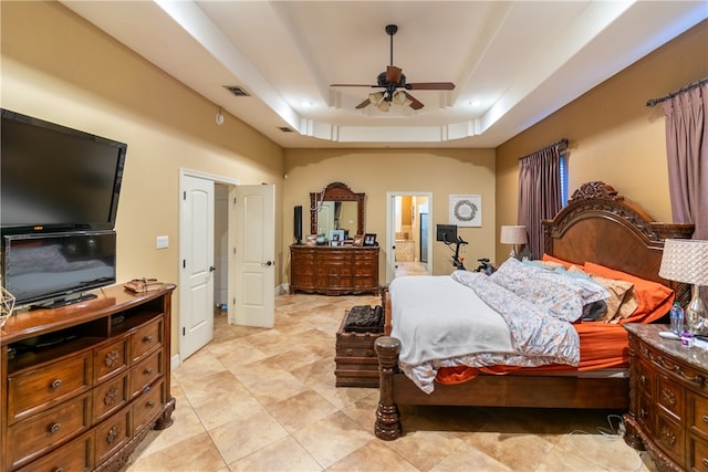 bedroom featuring ensuite bath, ceiling fan, and a tray ceiling