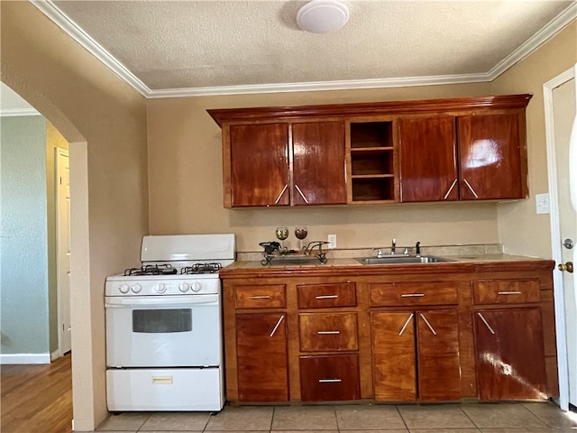 kitchen with sink, white gas stove, a textured ceiling, light tile patterned flooring, and ornamental molding