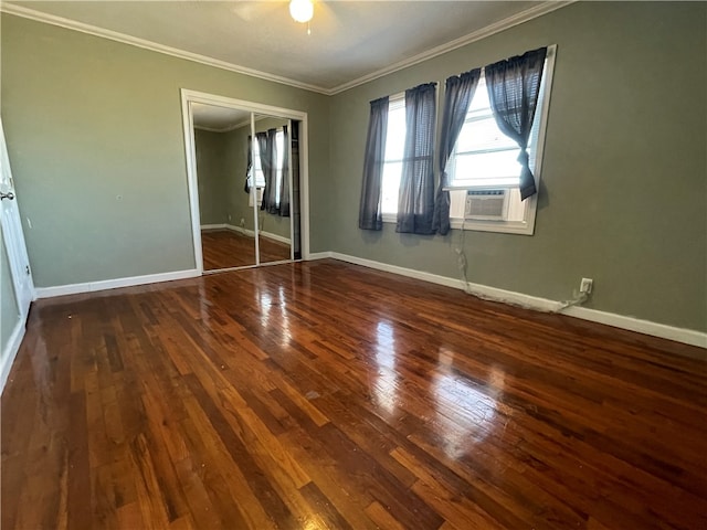 unfurnished bedroom featuring cooling unit, crown molding, dark wood-type flooring, ceiling fan, and a closet