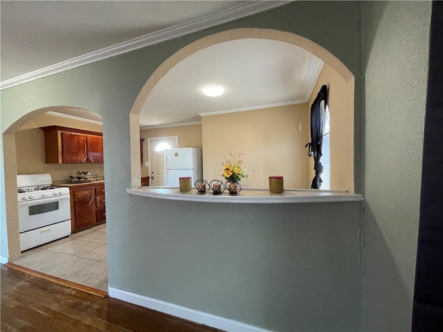 kitchen featuring white appliances, light hardwood / wood-style flooring, and crown molding