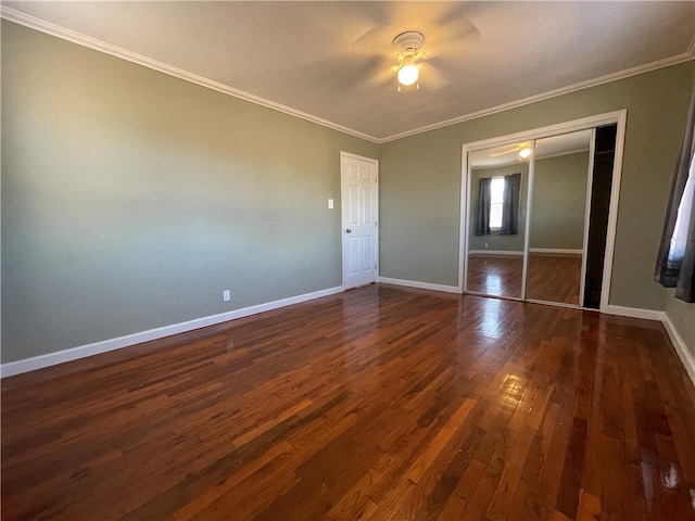 unfurnished bedroom with ceiling fan, ornamental molding, dark wood-type flooring, and a closet