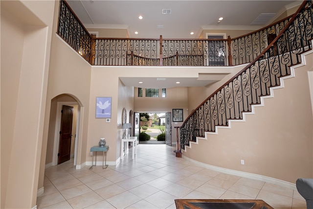 tiled foyer with crown molding and a towering ceiling