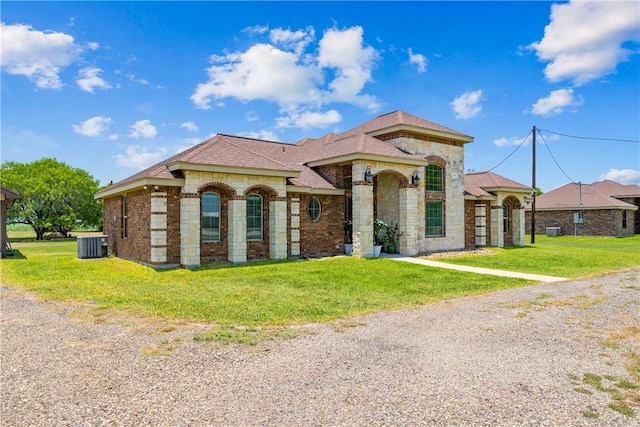 3941 Cobb Ln, Robstown, TX 78380 - mediterranean / spanish-style home featuring central AC unit, a front yard, stone siding, and a shingled roof