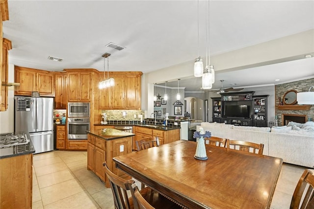 kitchen featuring stainless steel appliances, visible vents, open floor plan, dark countertops, and pendant lighting