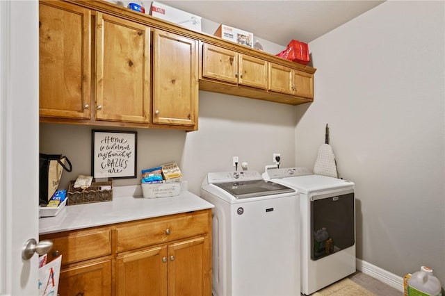 laundry room with cabinet space, baseboards, and washer and dryer