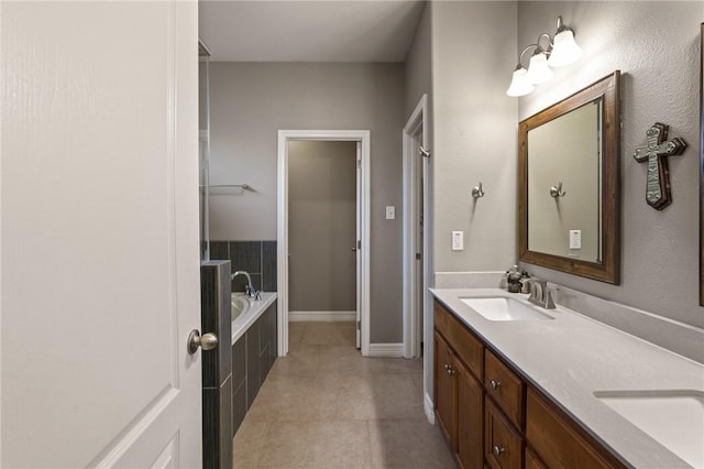 bathroom with double vanity, tile patterned flooring, a sink, and a bath