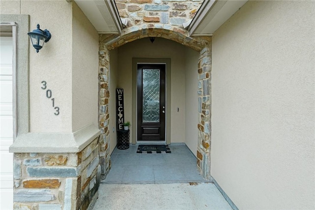 entrance to property with stone siding and stucco siding