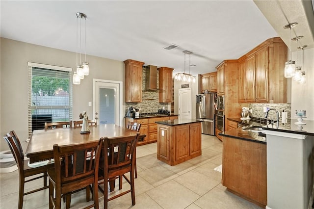 kitchen with stainless steel appliances, hanging light fixtures, wall chimney exhaust hood, and a center island