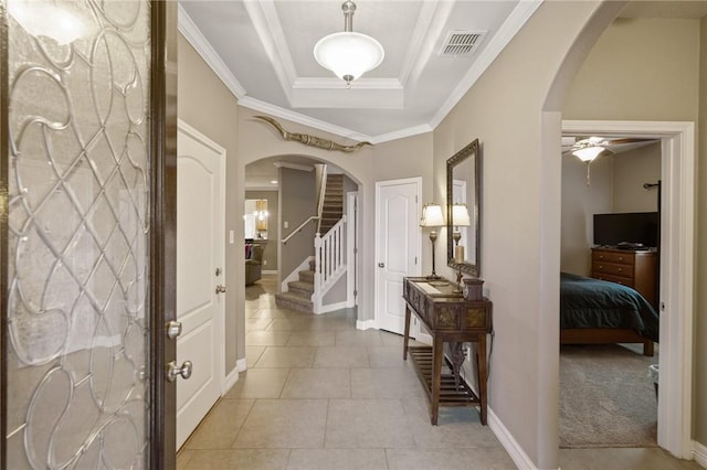 foyer entrance featuring arched walkways, light tile patterned floors, a raised ceiling, visible vents, and stairway