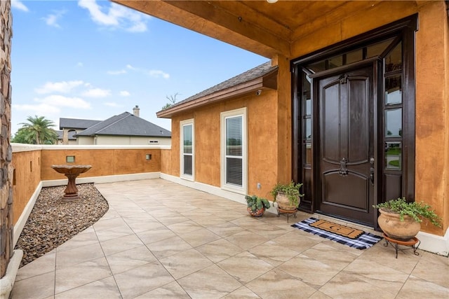 doorway to property with a shingled roof and stucco siding