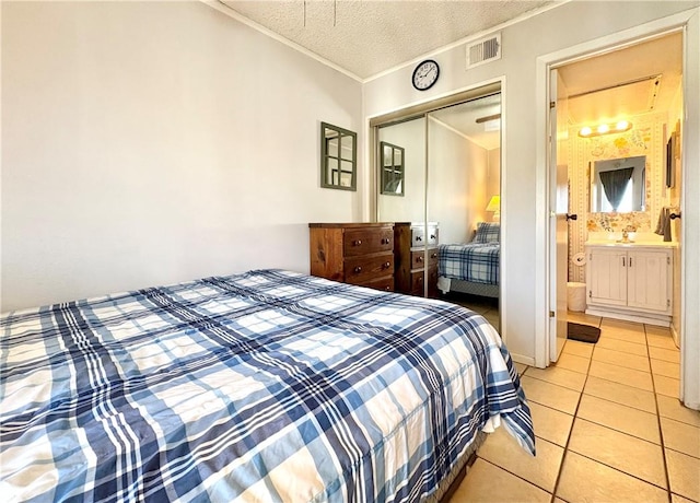 3938 Surfside Unit 3337, Corpus Christi, TX 78402 - bedroom featuring a closet, ornamental molding, light tile patterned flooring, a textured ceiling, and ensuite bath