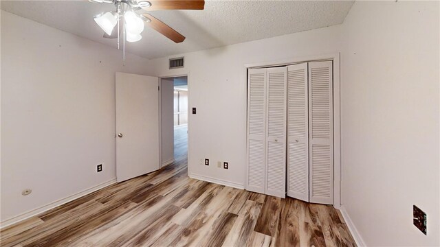 unfurnished bedroom with ceiling fan, a textured ceiling, a closet, and light wood-type flooring