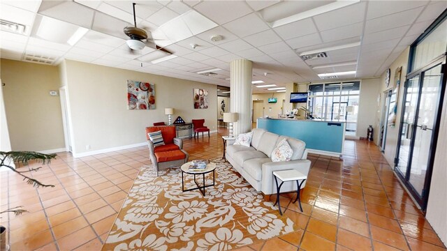 living room featuring ceiling fan, tile patterned floors, and a drop ceiling