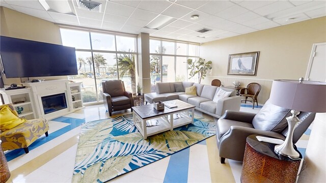 living room featuring plenty of natural light, a paneled ceiling, and floor to ceiling windows