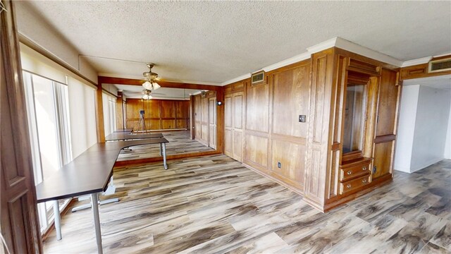 interior space with light wood-type flooring, wooden walls, and a textured ceiling