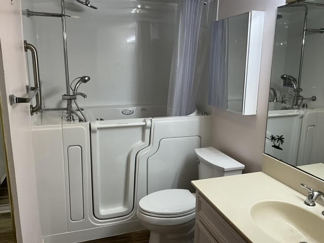 full bathroom with hardwood / wood-style flooring, vanity, toilet, and independent shower and bath